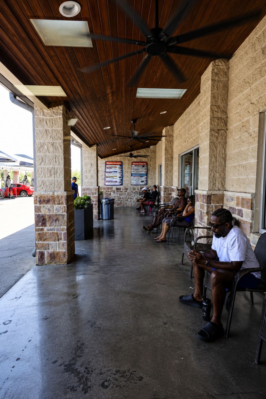Covered stone porch with ceiling fans and customers seated in the shade